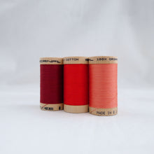 Load image into Gallery viewer, Three wooden reels of Scanfil Organic Cotton Thread in Wine, Ruby, Salmon colours.
