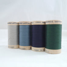 Load image into Gallery viewer, Four wooden reels of organic sewing cotton. Sand, Stormy Blue, Midnight, Forest.
