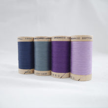Load image into Gallery viewer, Four wooden reels of Scanfil Organic Cotton Thread in Sapphire, Dusk, Purple and Lavender colours.
