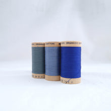Load image into Gallery viewer, Three wooden reels of Scanfil Organic Cotton Thread in Stormy Blue, Dusk, Ocean colours.
