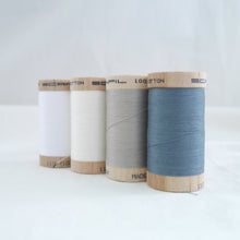 Load image into Gallery viewer, Four wooden spools of organic cotton sewing thread in the colours white, natural, grey, and blue.
