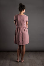 Load image into Gallery viewer, Back view of lady standing, wearing fitted short sleeve bodice, with gathered waistline skirt, knee length dress.
