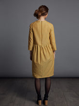 Load image into Gallery viewer, Back view shows drop shoulders at back, with gathered waistline and invisible zip at centre back seam of the knee-length dress.
