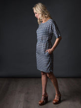 Load image into Gallery viewer, Side view of lady wearing sheath dress with hand in pocket.
