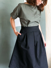 Load image into Gallery viewer, Close up of lady wearing black three pleat skirt, with hand in side pocket.
