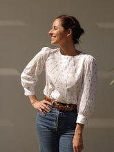Load image into Gallery viewer, Lady wears a white Zenith blouse with hand on hip. Paired with denim jeans.
