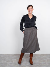 Load image into Gallery viewer, Front view of lady wearing an A-line midi skirt with hands in pockets
