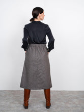 Load image into Gallery viewer, Back view of lady wearing A-line Midi Skirt with hands in pockets
